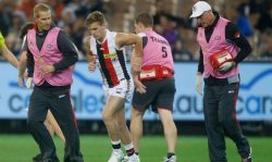 Andrew Wallis and Tim Barbour assisting player Jack Lonie in a St Kilda FC match last year.