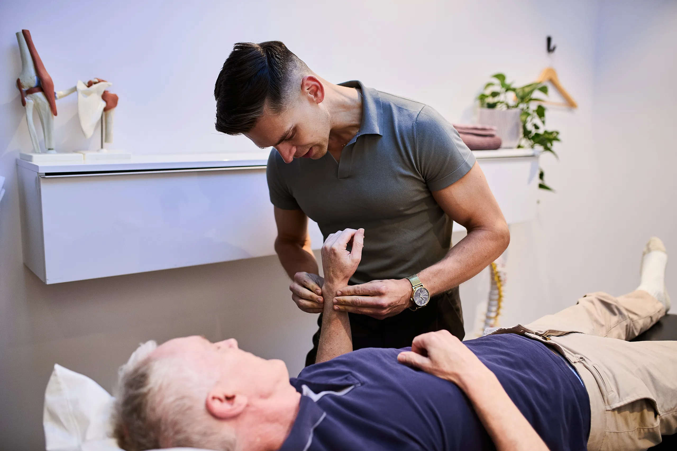 Pure Physio physiotherapist Jacob Stefanoff performs spinal palpation on a senior male client during a physical examination at Collins Street clinic.