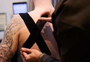 Pure Physio physiotherapist Jacob Stefanoff applies manual therapy to a client's shoulder and upper back during treatment at Collins Street clinic.