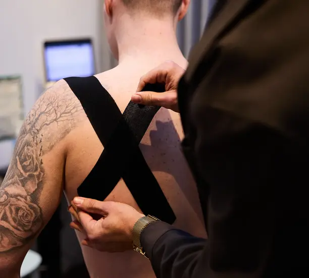 Pure Physio physiotherapist Jacob Stefanoff applies manual therapy to a client's shoulder and upper back during treatment at Collins Street clinic.