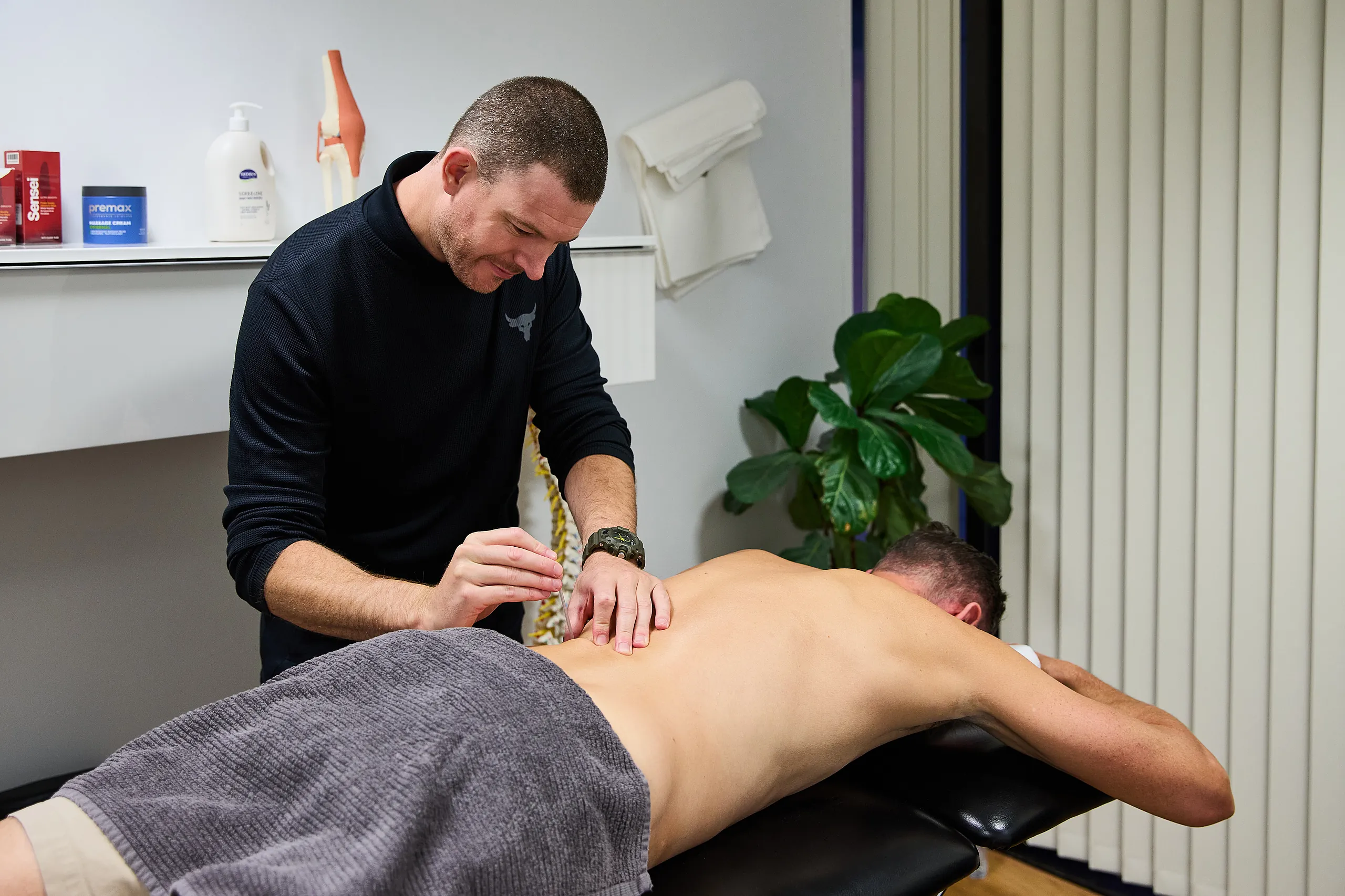 Pure Physio physiotherapist Andrew Brady instructs a client on a therapeutic shoulder exercise in the Queen Street clinic treatment room.